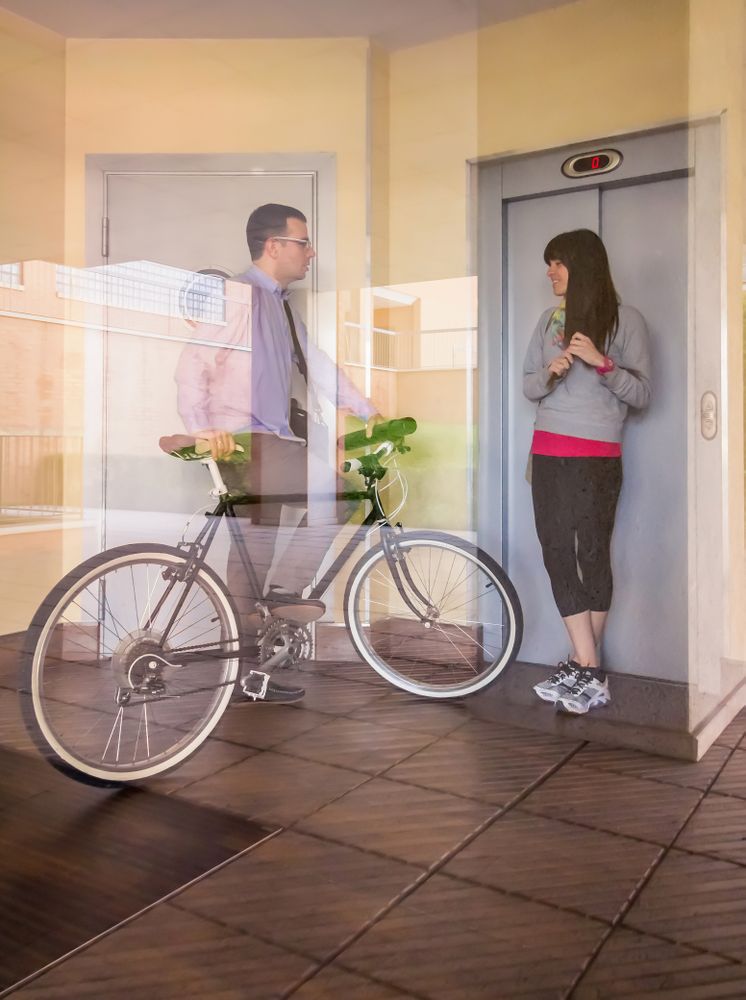 Businessman and sportive woman waving behind glass