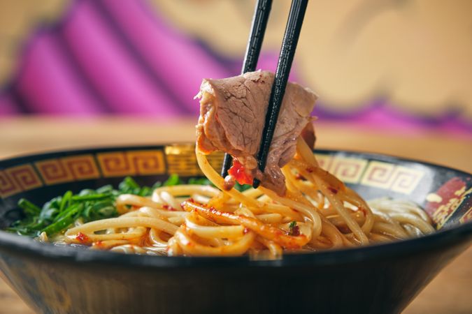 Tasty ramen with tender pork slice between chopsticks