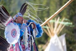 Montana, United States - August 17, 2022: Native man in full regalia performing with microphone
