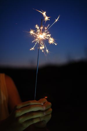 Crop person with sparkler at night