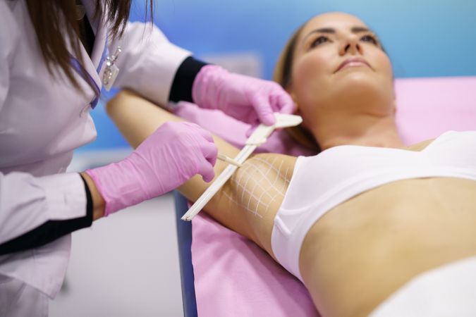 Woman lying down with arm up for hyperhidrosis treatment