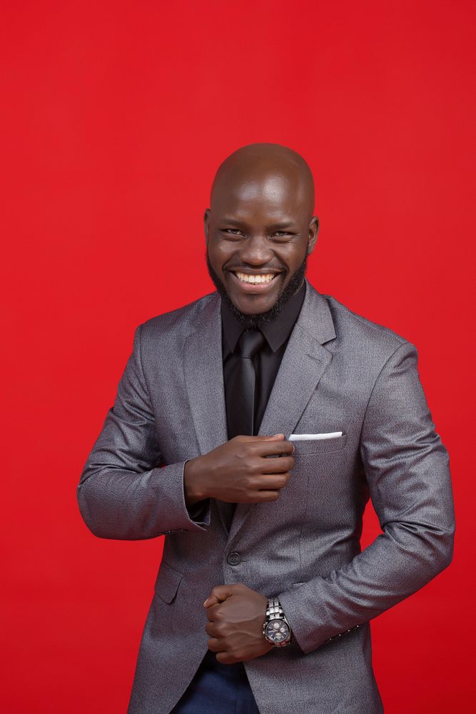 Man in gray suit jacket smiling with red background