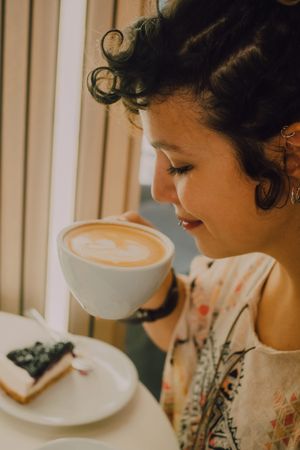 Positive woman drinking coffee in cafe