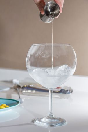 Barman pouring drink to prepare gin tonic cocktail