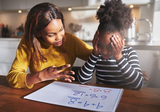 Black mother and daughter work through a frustrating math problem at home