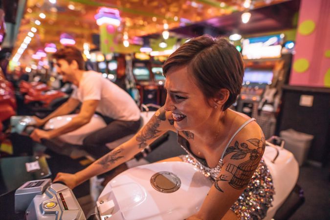 Woman playing a racing game sitting on an arcade racing bike at a gaming parlour