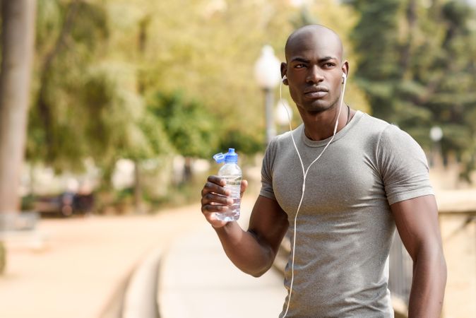 Fit male drinking from a water bottle in an outdoor park
