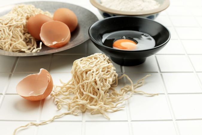 Eggs, flours and noodles on tile counter