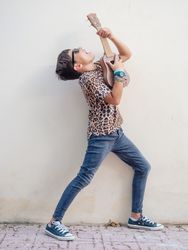 Excited kid raising hands up with ukulele