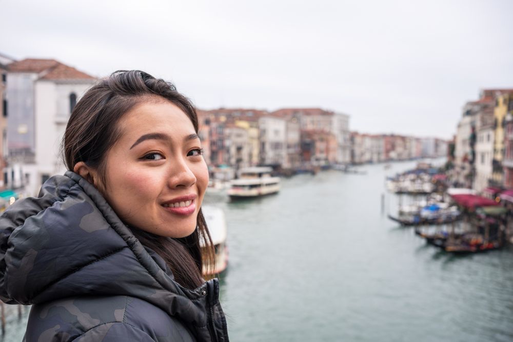 Satisfied Asian resting woman exploring old city with waterways