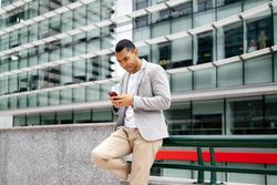 Man using smartphone leaning against wall