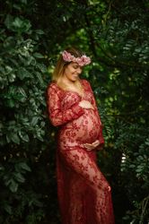 Pregnant woman with closed eyes touching belly and chin while standing in garden in sunny day