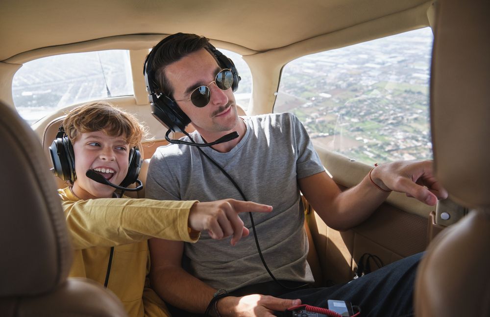 Cheerful kid with father pointing away during flight in airplane