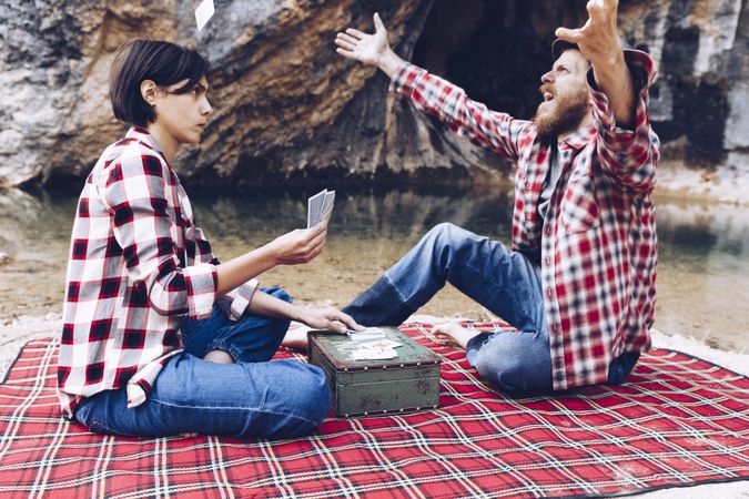 Casual couple playing cards on shore