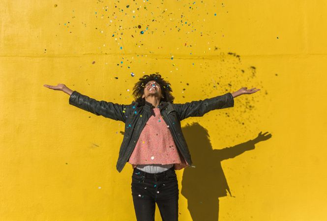 Black woman with afro hair celebrating with confetti.