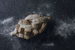 Loaf of bread with incisions on grey texture background