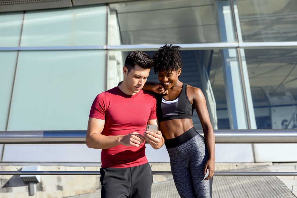 Sportsman showing app on smartphone to sportswoman