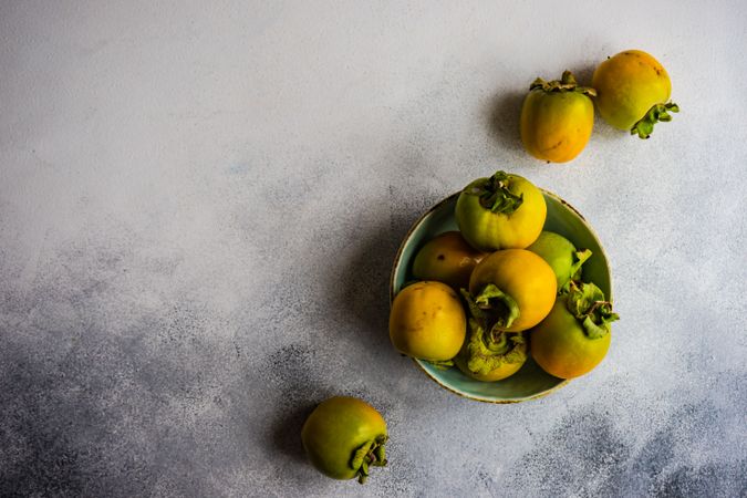 Top view of bowl of persimmons on marble counter