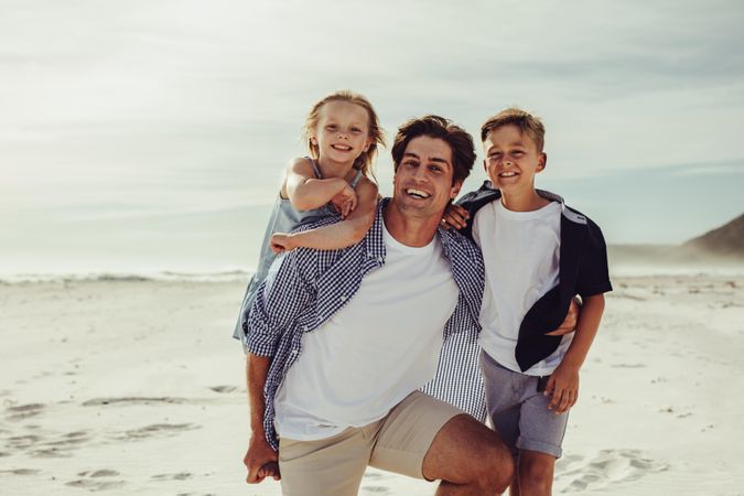 Happy man with his two kids on the beach