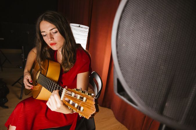 Creative woman singing and playing guitar on stage