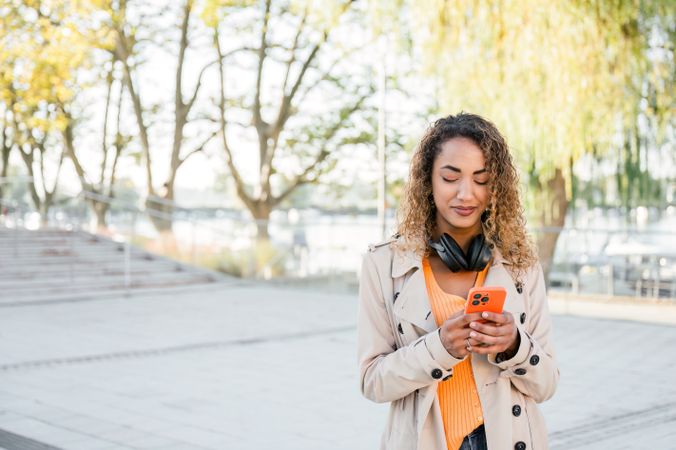 Smiling woman using smartphone on street