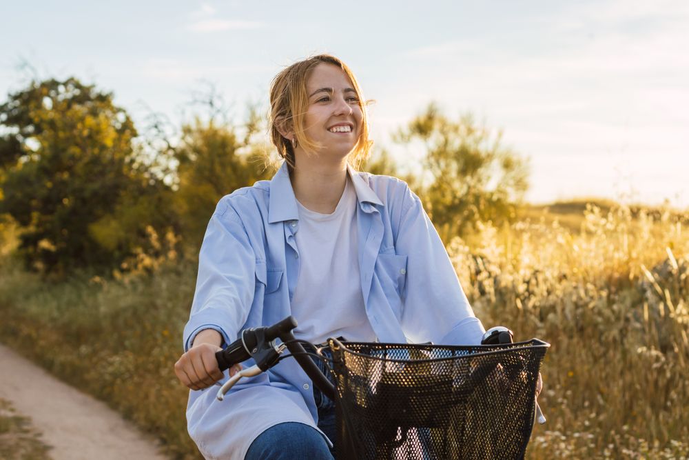 blonde young woman cycling on a field. sunset