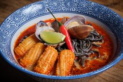 Typical hot ramen dish with fish broth in a bowl with noodles, squid, chilli, clams.