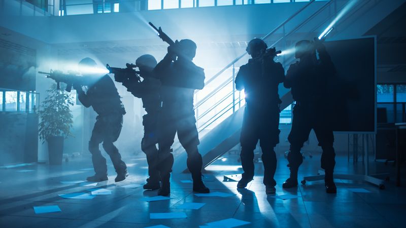 Masked Fireteam of Armed SWAT Police Officers Storm a Dark Seized Office Building with Desks and Computers.