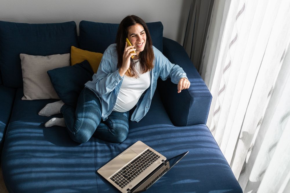 Pregnant woman talking on smartphone during remote work