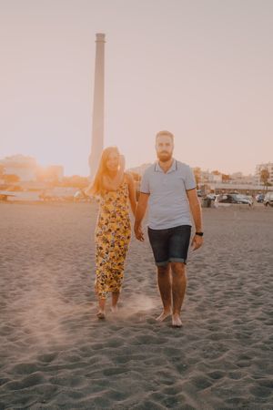 Lovely couple walking holding hands on sandy beach