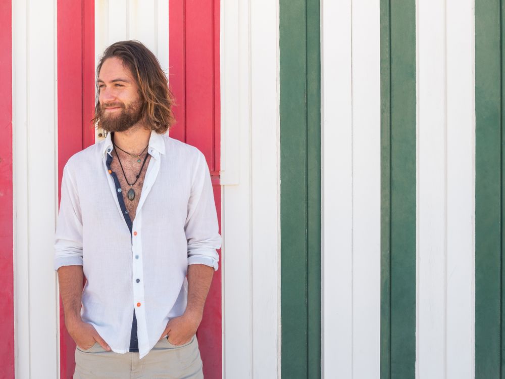Cheerful guy standing near striped wall