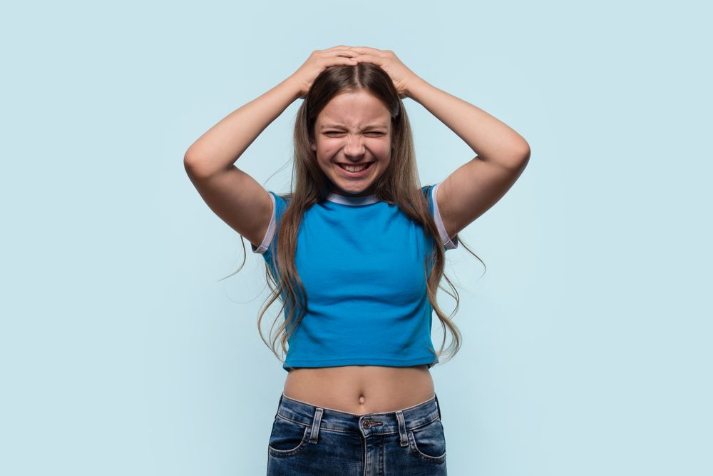 Girl holding head in frustration or pain, expressing discomfort
