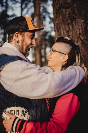 Happy couple hugging and kissing near tree in park