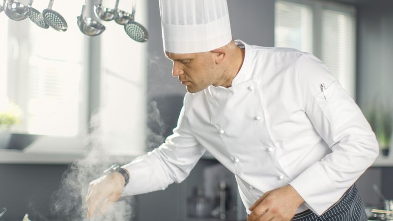 Famous Restaurant Chef Stirs Soup or Sauce in a  Saucepan. His Preparing Dishes in Modern Kitchen.