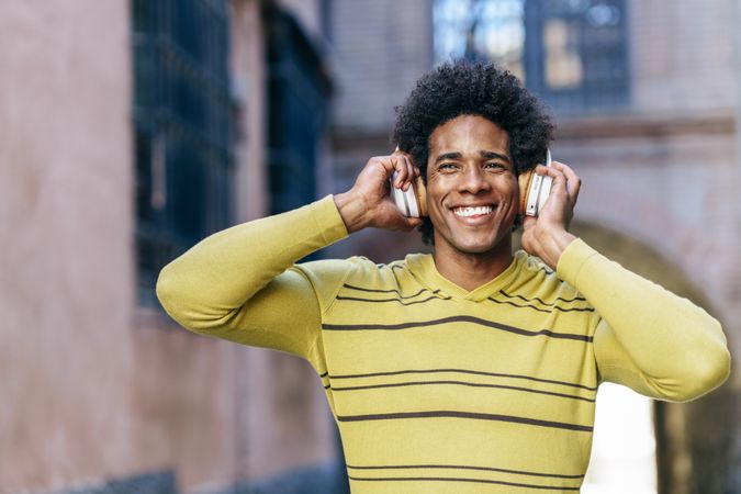 Man holding headphones to his ears and smiling
