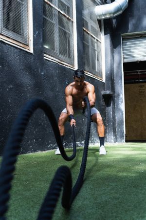 Strong Hispanic woman exercising with battle ropes