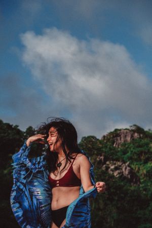 Smiling woman in red bikini and blue shirt standing outdoor