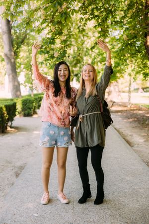 Cheerful multiethnic women greeting friend in park