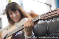Female hand strumming acoustic guitar in bright loft 0Plzv0