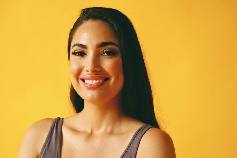 Smiling Hispanic woman looking confidently at camera in yellow room