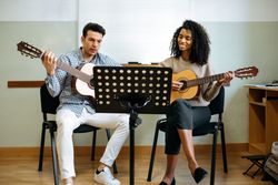 Man and woman playing guitar in studio