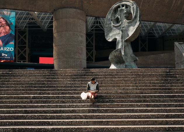 Man sitting alone on staircase outside large center