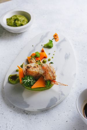 grilled scorpion fish with mashed peas and carrot sticks, on a marble plate