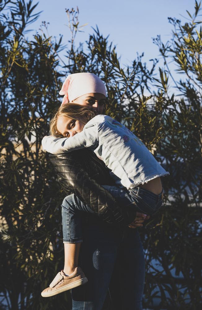 Woman holding girl with cancer headwrap