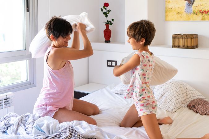 Mother having a fun pillow fight with her daughter