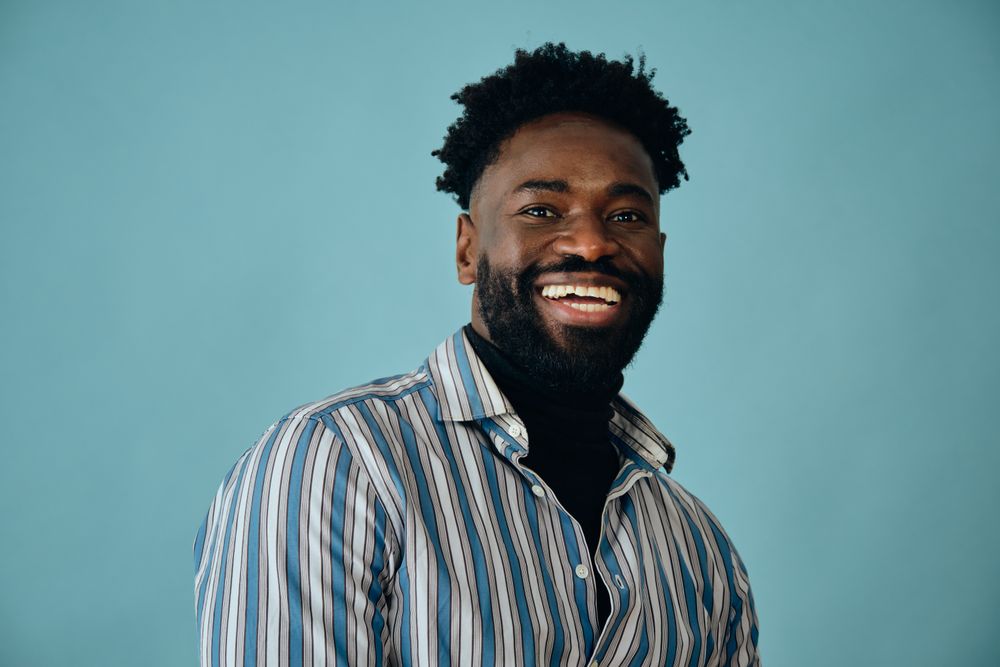 Closeup portrait of a smiling Black man in blue studio shoot