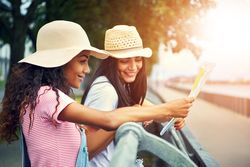 Happy female friends exploring park using a paper map