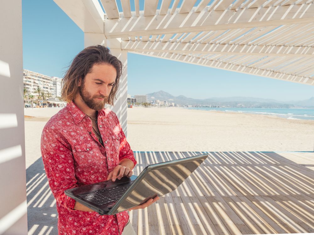 Man using laptop on beach