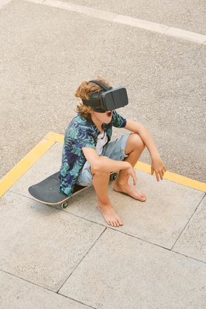 Boy in VR headset sitting on skateboard