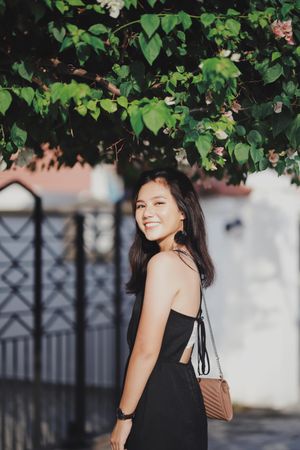 Side view of smiling woman in dark dress standing outdoor